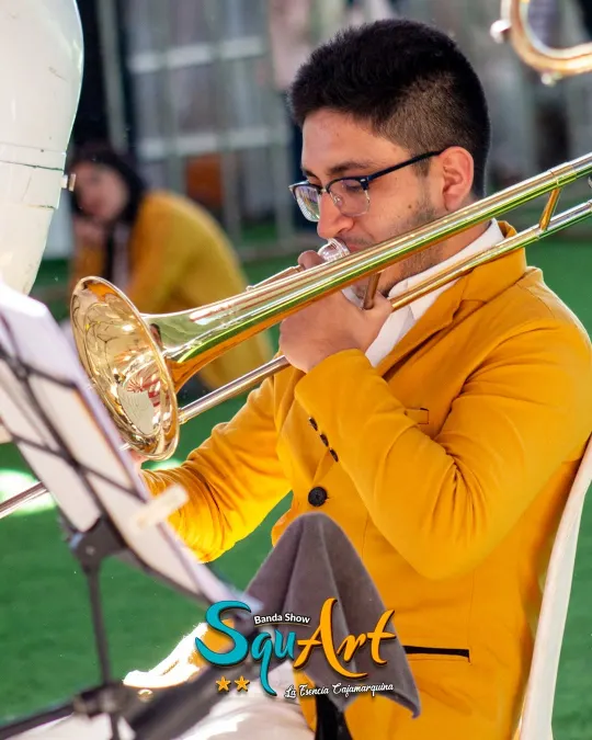 Músico de la banda tocando el trombón junto al atril